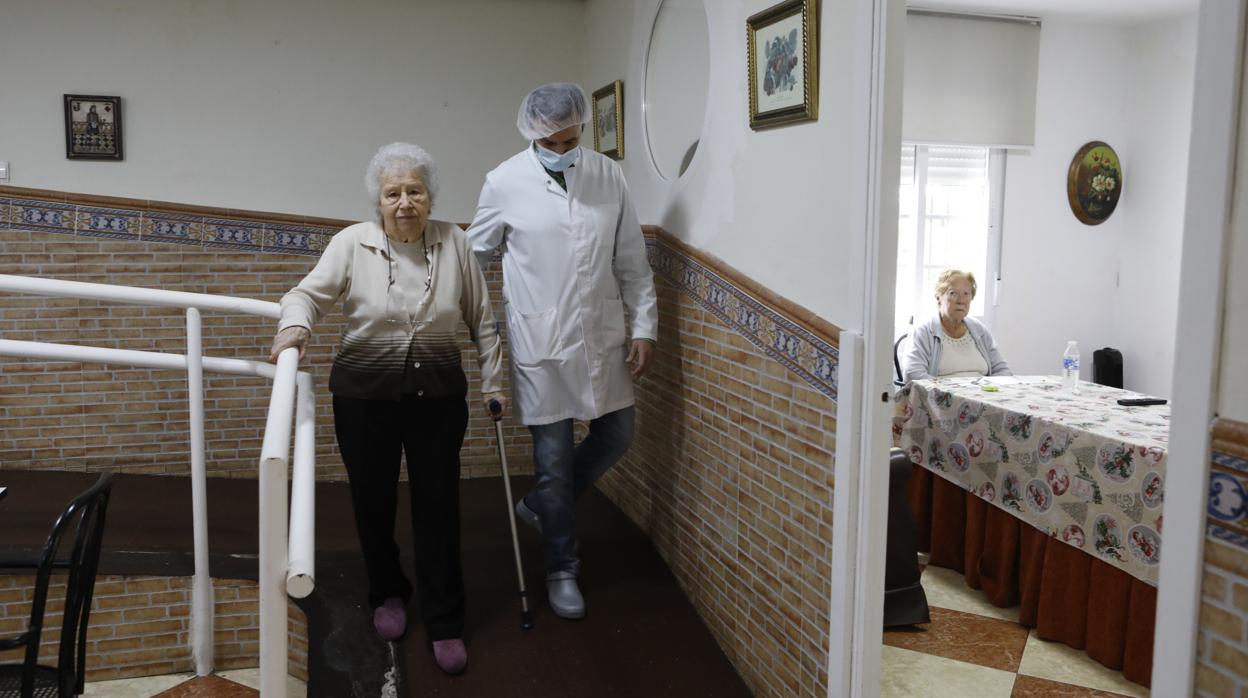 Un trabajador acompaña a una residente en un centro de mayores