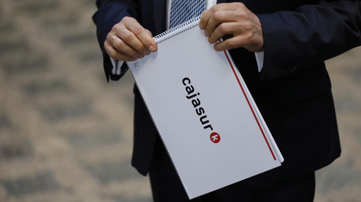 Un directivo de Cajasur sostiene una libreta con un balance