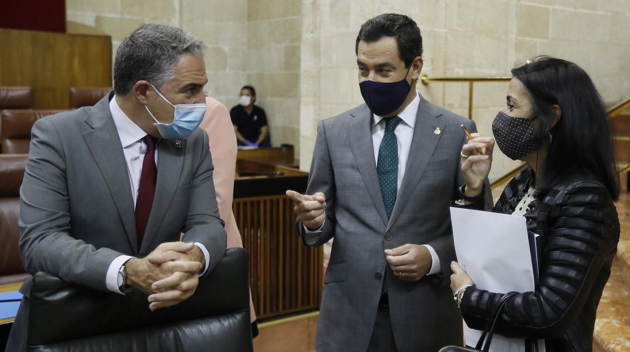 El presidente andaluz, Juanma Moreno, bromea con Elías Bendodo en presencia de la presidenta del Parlamento, Marta Bosquet