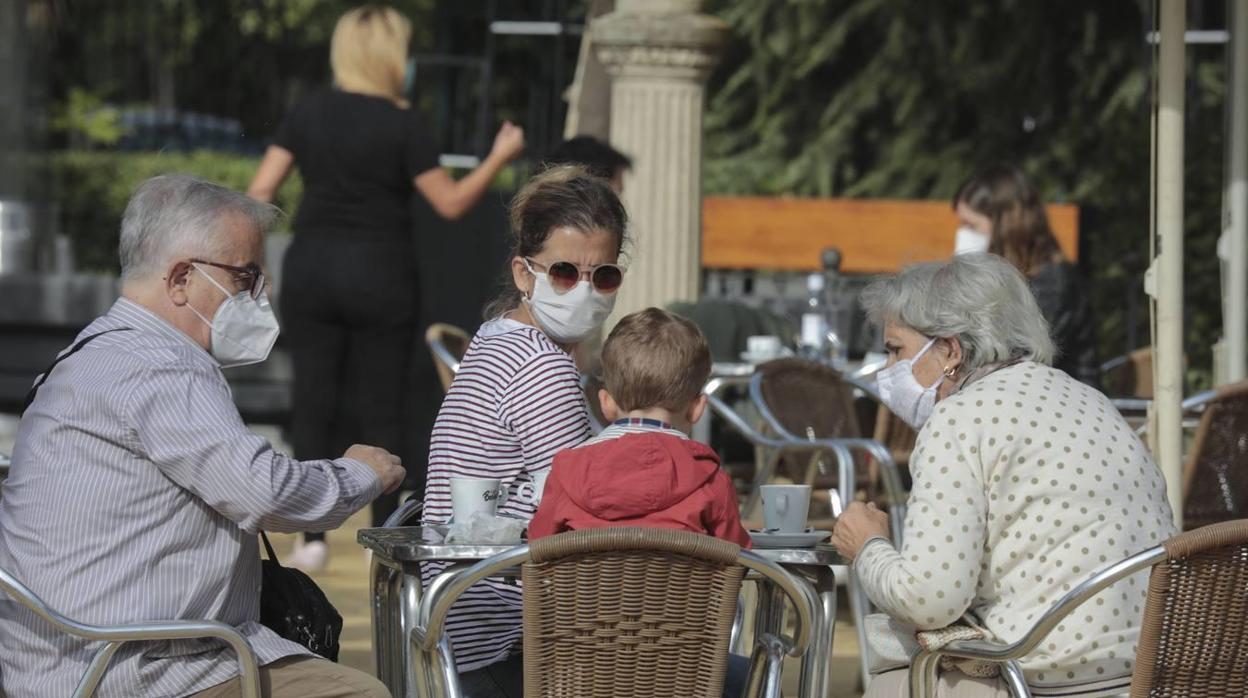 Una familia con mascarilla en el velador de un bar de Sevilla
