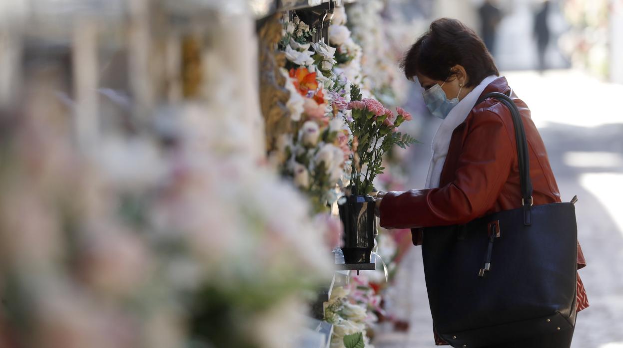 Una mujer pone flores en el cementerio de San Rafael
