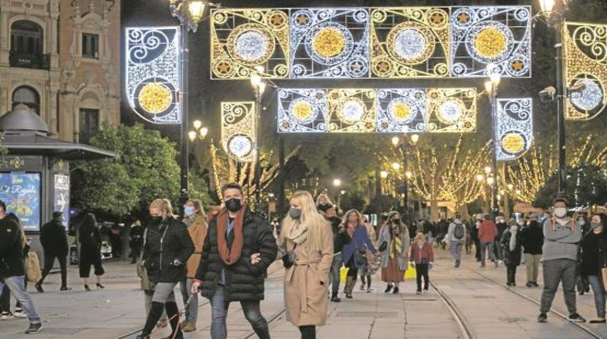 Varios sevillanos pasean por el Centro de la ciudad bajo la iluminación navideña