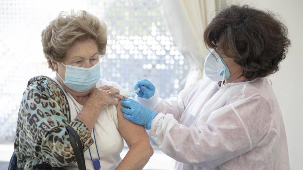 Una enfermera administra una dosis de la vacuna de la gripe a una señora residente en un centro de mayores