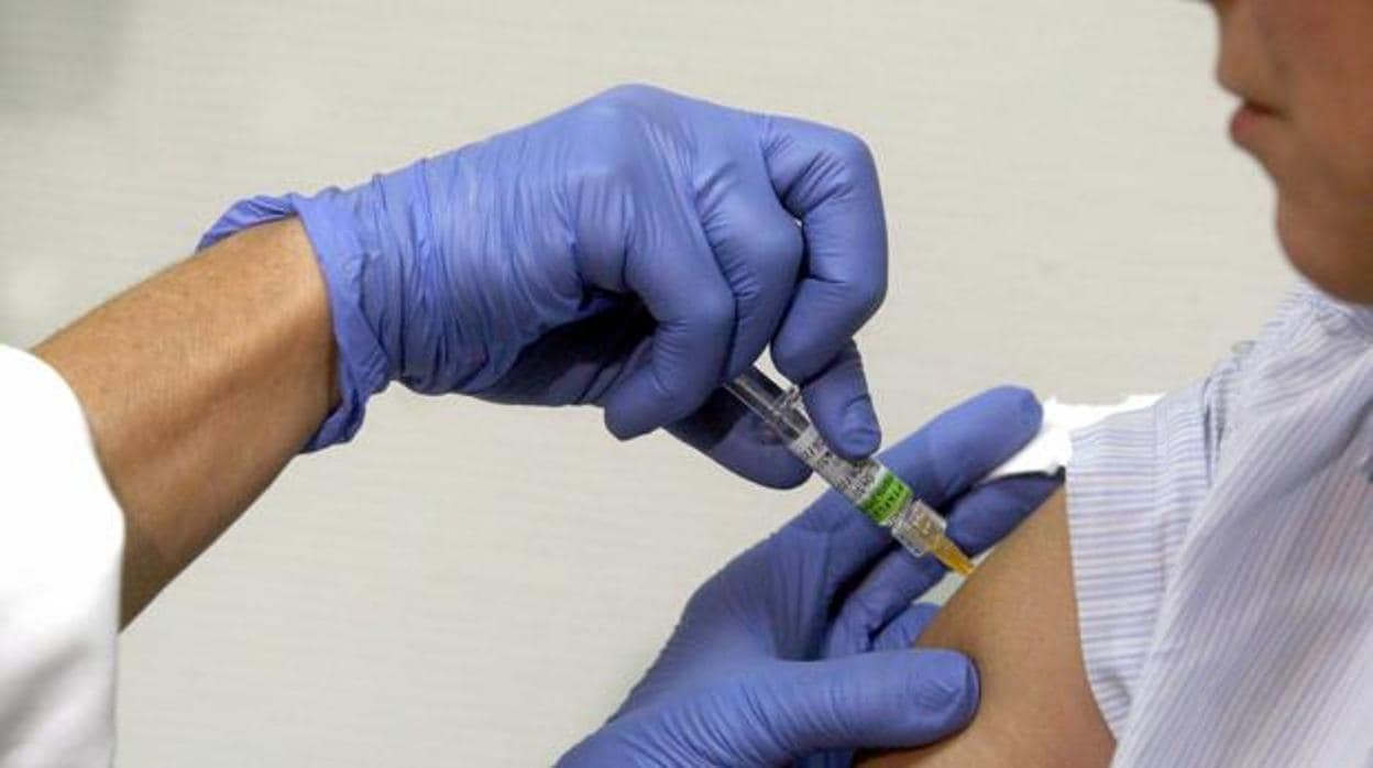 Un facultativo poniendo una vacuna contra la gripe