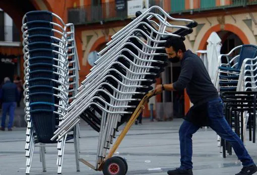 Un trabajador de hostelería recoge la terraza de su bar en Córdoba