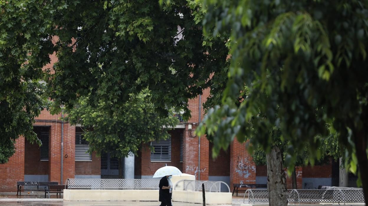 Una mujer pasea con un paraguas en un patio de Las Moreras