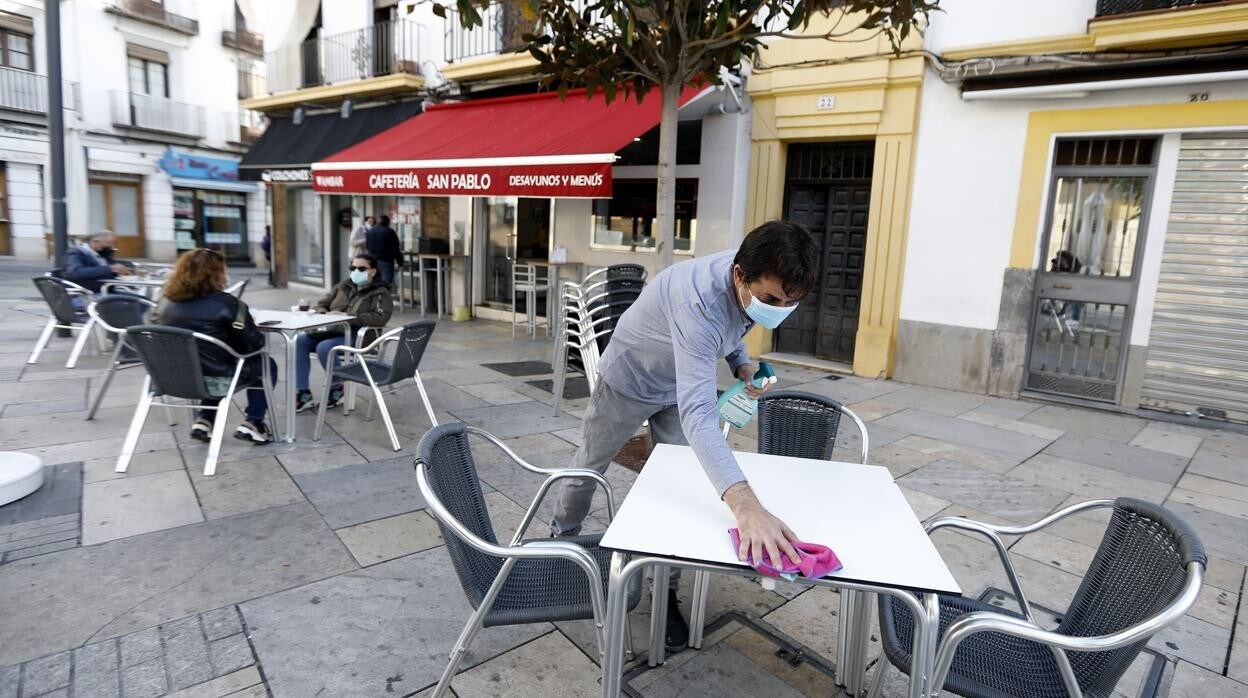 Un camarero con mascarilla limpia una mesa en San Pablo