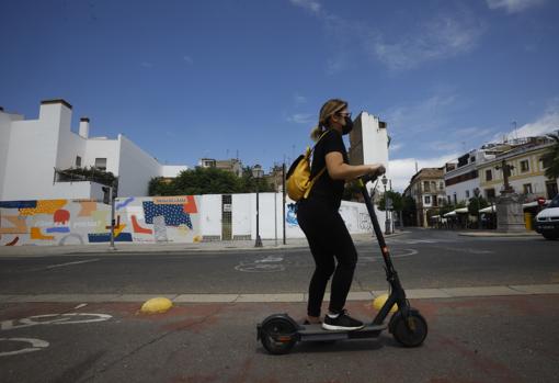 Una mujer circula con su patinete eléctrico por la Ribera