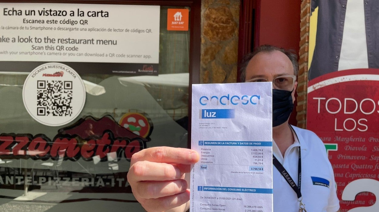 Alessandro Imperiali, dueño de Pizzametro, sostiene la factura que podría avocar al cierre del negocio