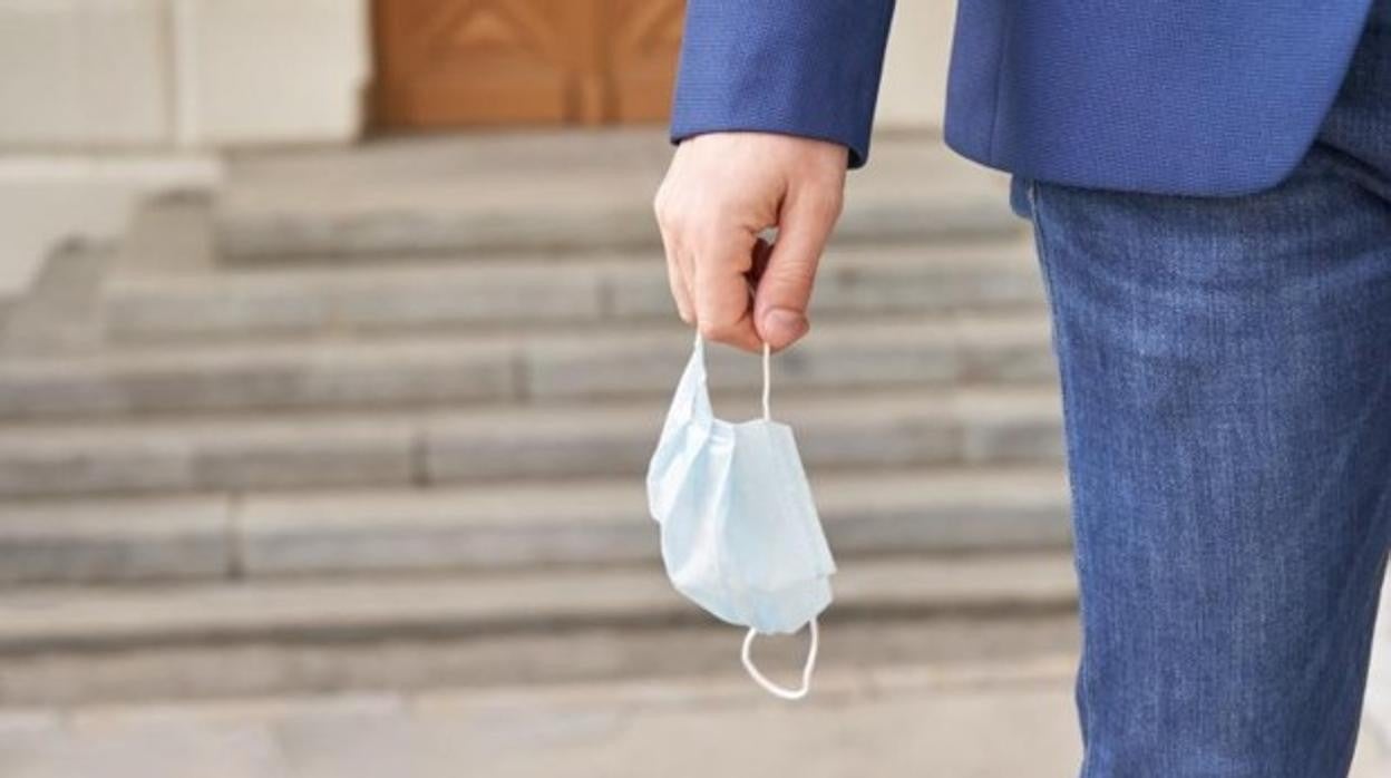 Un hombre con la mascarilla en la mano al estar en exterior