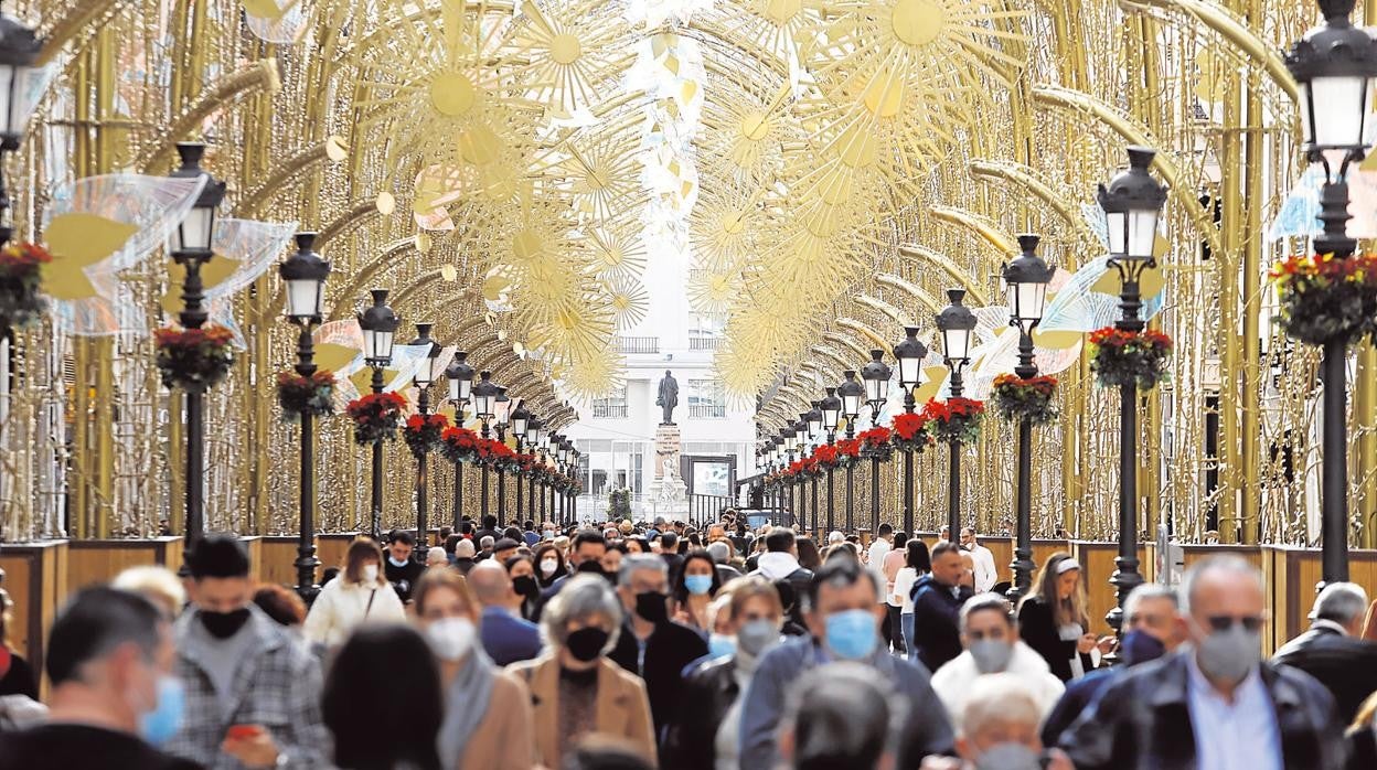 Ciudadanos paseando por las calles de Málaga bajo la decoracón navideña