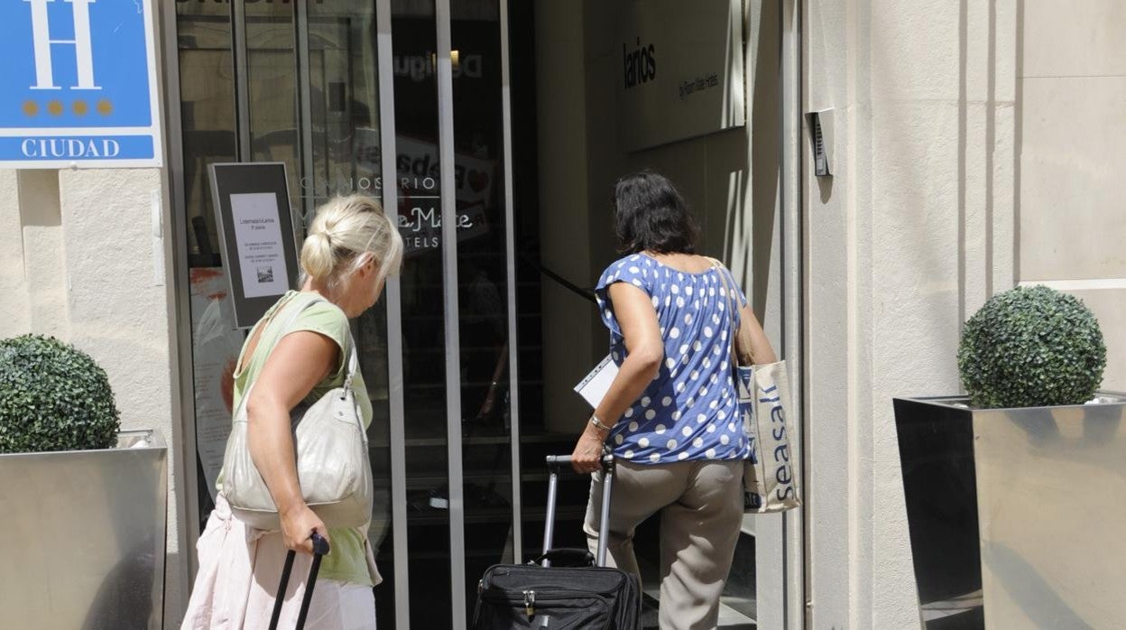 Dos turistas llegan a su hotel portando sus maletas en el centro de Málaga