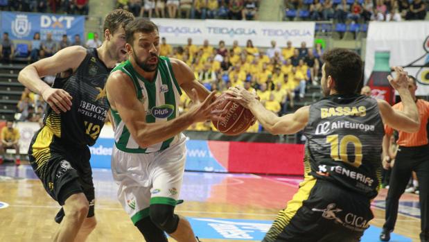 Strahinja Milosevic, del Real Betis Enegía Plus, supera al ala-pívot A. Doornekamp (i) y a Ferrán Bassas (d), del Iberostar Tenerife