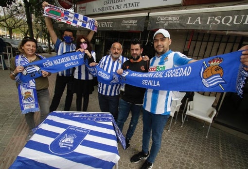 Varios miembros de la Peña Nazarena de la Real Sociedad posan en su lugar habitual de reunión, el bar 'La Esquinita del Puente', con banderas y bufandas del cuadro realista