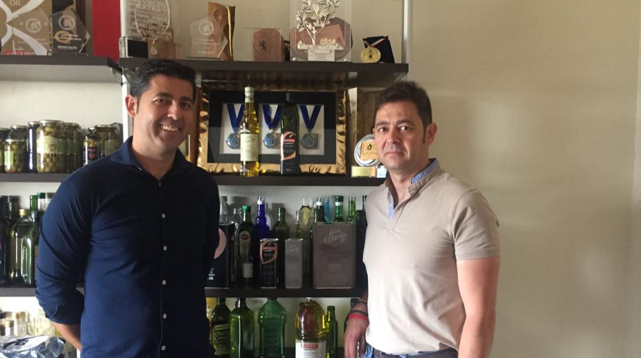 José Manuel Muela y su hermano Mateo, ante un expositor con sus premiados aceites de oliva virgen extra