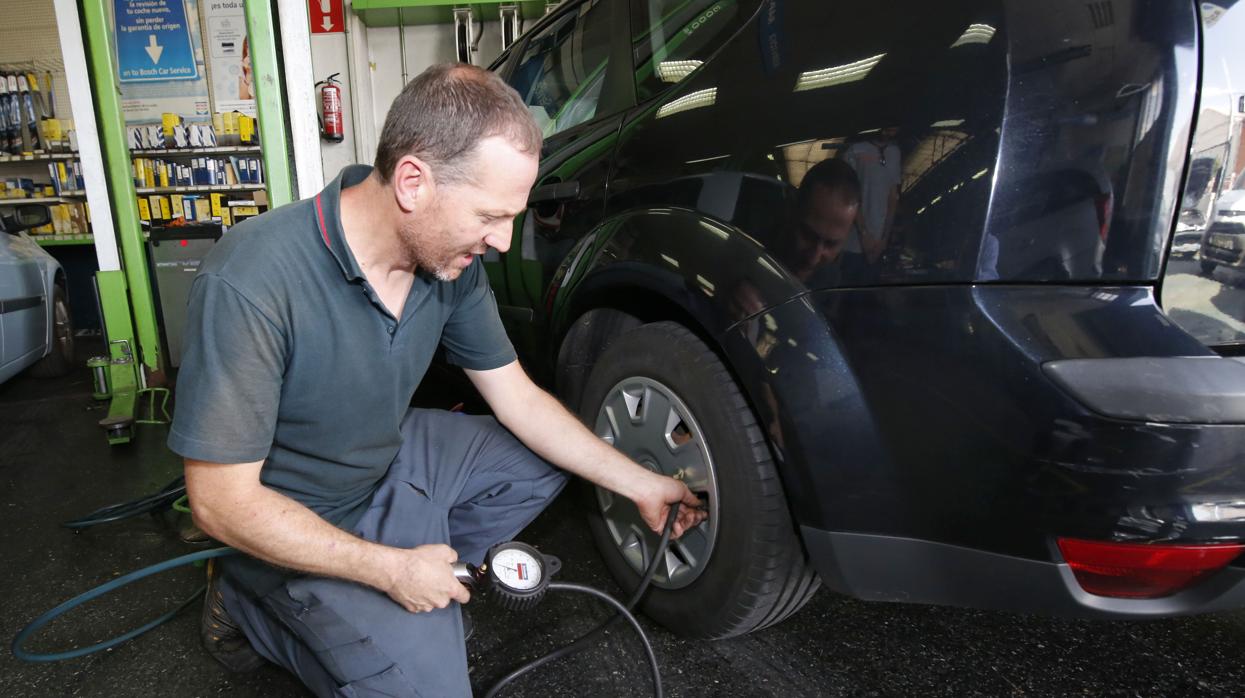 Un trabajador infla la rueda de un coche en un taller