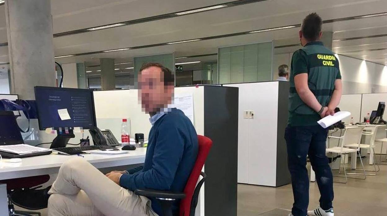 Un trabajador de Abengoa espera instrucciones junto a un guardia civil durante el registro en las oficinas