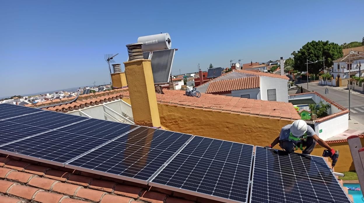 Un instalador coloca paneles solares para autoconsumo en una vivienda