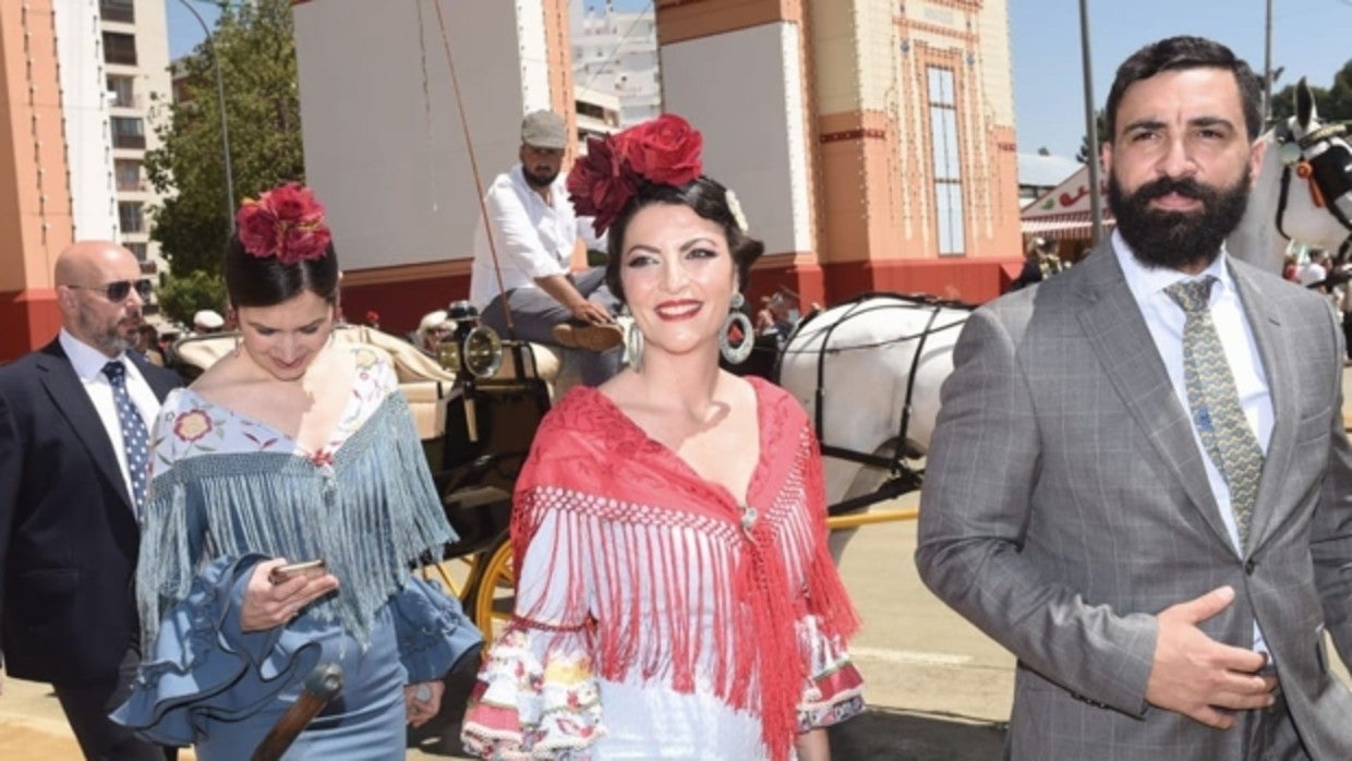 Macarena Olona, ataviada con el traje de flamenca, junto a la portada de la Feria de Sevilla