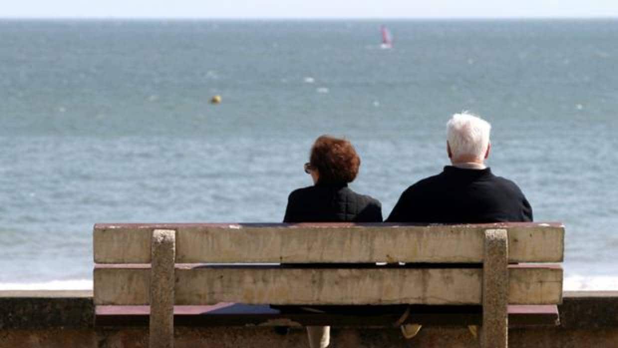 Una pareja de pensionistas descansa en un banco frente al mar