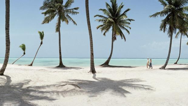 Una pareja pasea en una playa paradisíaca de arenas blancas