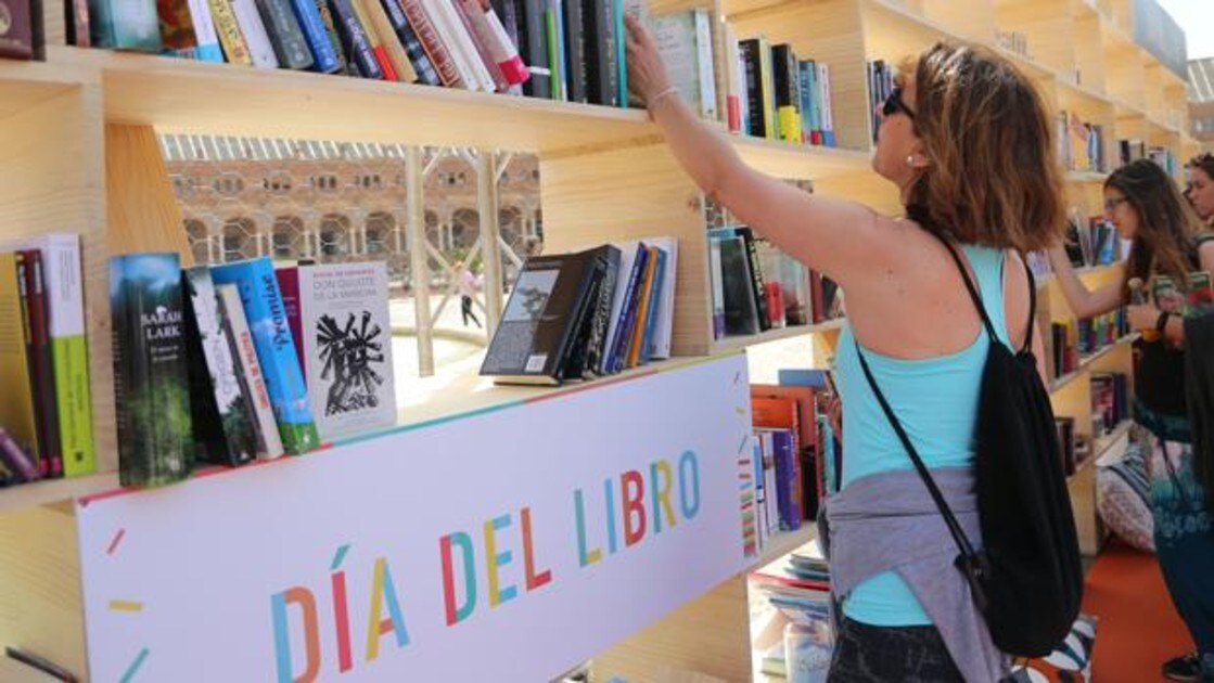 Una mujer selecciona una obra dentro de los actos organizados por el Día del Libro en Sevilla