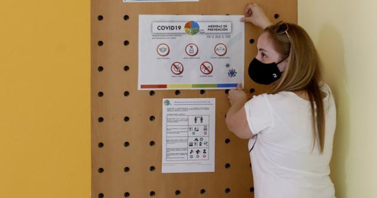 Una profesora coloca instrucciones para prevenir el Covid en un colegio de Córdoba