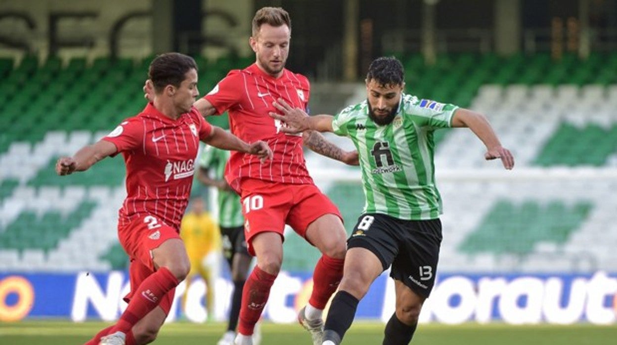 Nabil Fekir trata de avanzar ante Montiel y Rakitic durante el derbi Betis - Sevilla