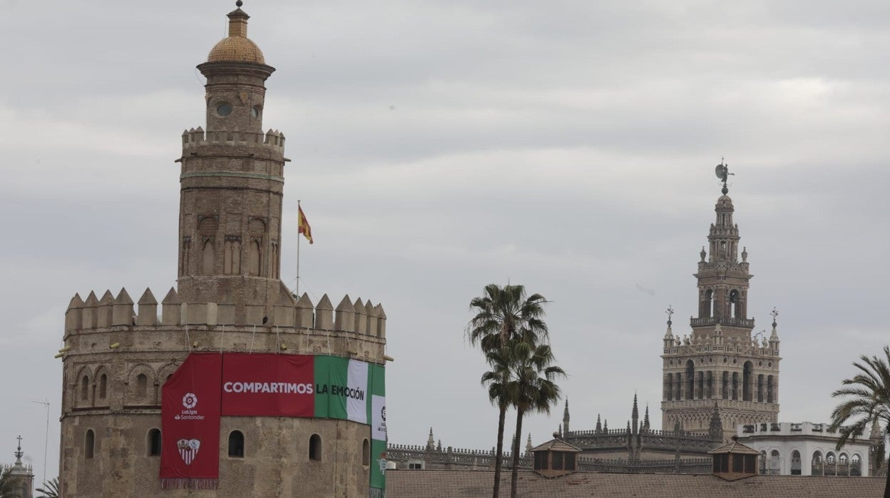 En primer plano la Torre del Oro con la bufanda del derbi Sevilla - Betis