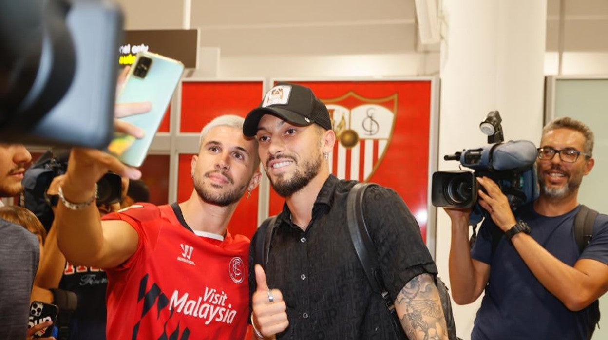 Alex Telles posa con un aficionado sevillista para una fotografía a su llegada al aeropuerto de Sevilla