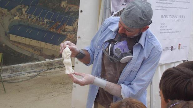 Un escultor muestra una de sus piezas a unos niños