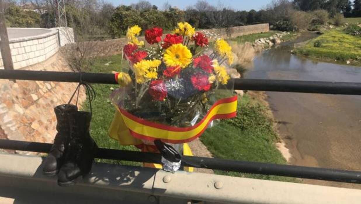 Un ramo de flores, unas botas y una bandera colocados sobre el puente donde murió ahogado Diego Díaz