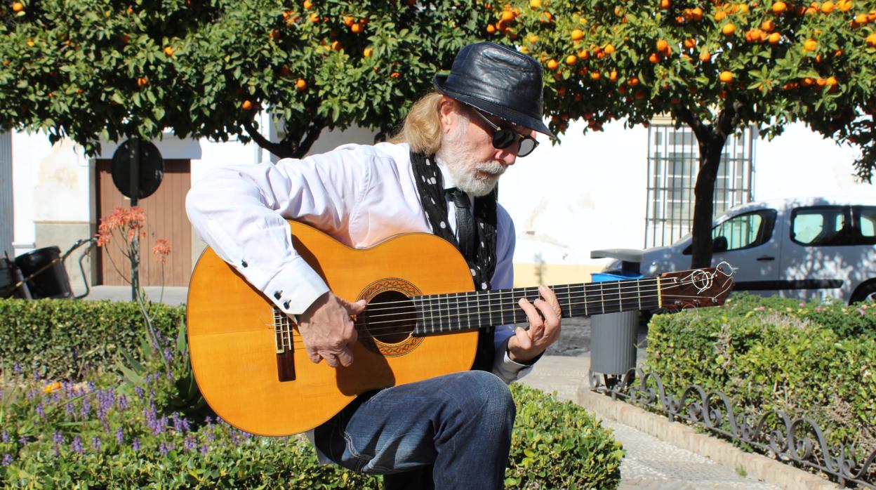 El utrerano Ramón Priego acaricia su guitarra en la plaza Enrique de la Cuadra de su localidad natal