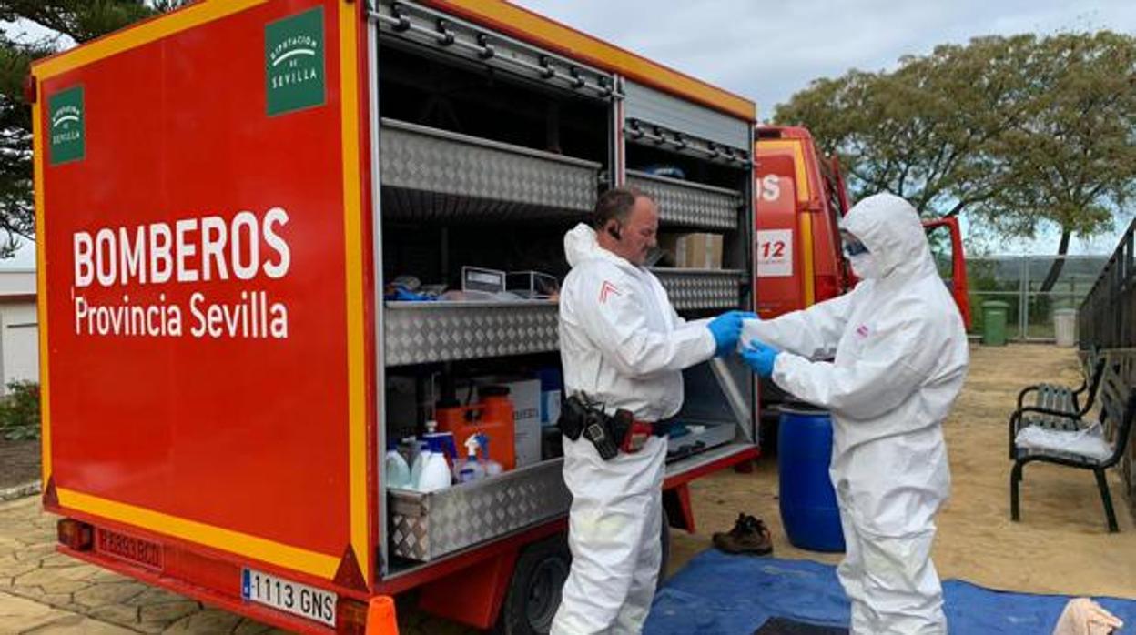 Dos bomberos de la Diputación de Sevilla se preparan para realizar tareas de desinfección