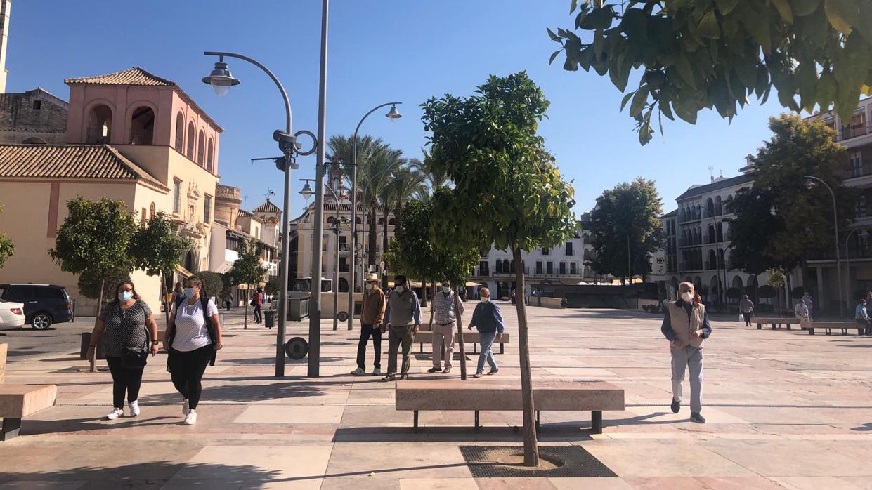 Varias personas transitan por una de las plazas principales de Écija, 24 horas antes de ser confinada