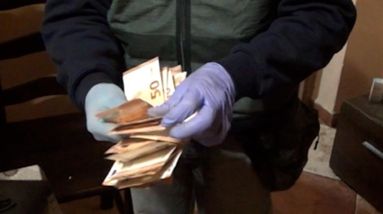 Un agente cuenta el dinero intervenido en uno de los registros domiciliarios