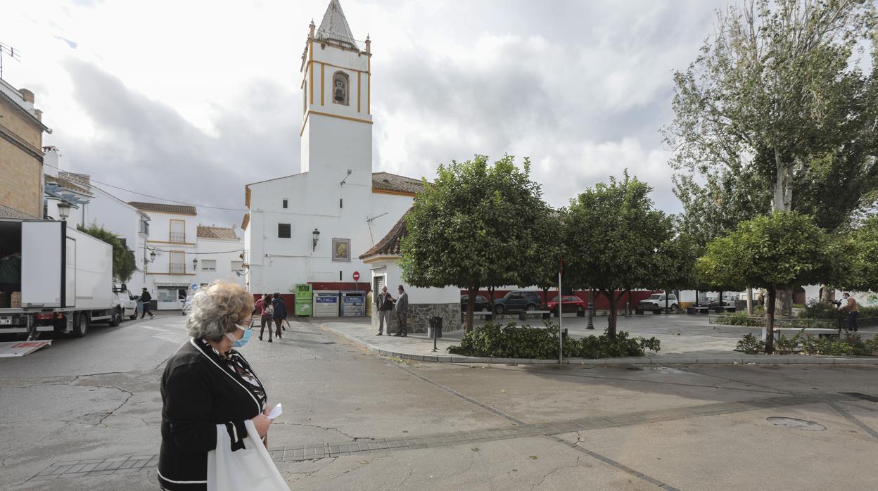 Una mujer pasea por la plaza de la iglesia del municipio sevillano de Pruna