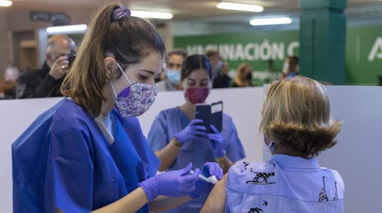 Una sanitaria administra una vacuna a una mujer en el vacunódromo del estadio de la Cartuja