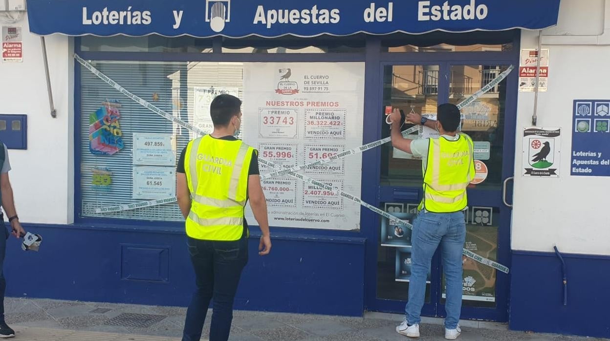 Dos agentes proceden a precintar la administración de loterías de El Cuervo