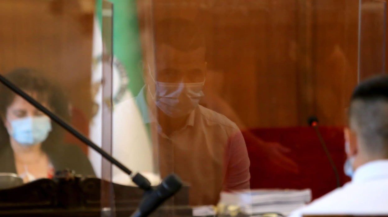 El rostro del acusado reflejado en la mampara instalada en la sala de vista por el coronavirus