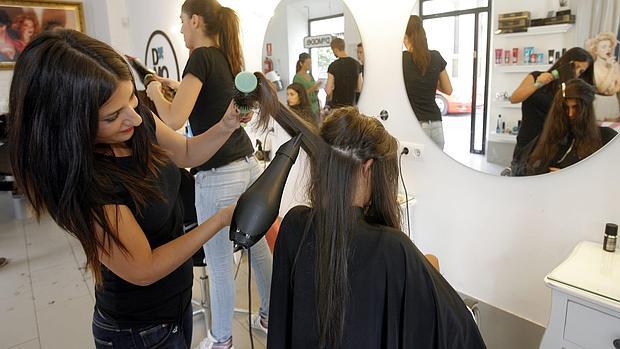 Una peluquera atiende a su cliente