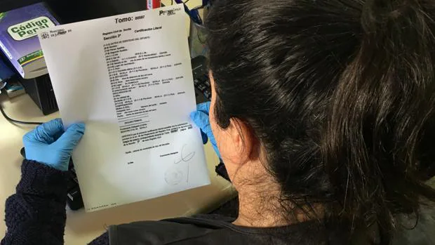 Un agente revisa uno de los documentos que firmó la detenida en lugar del difunto