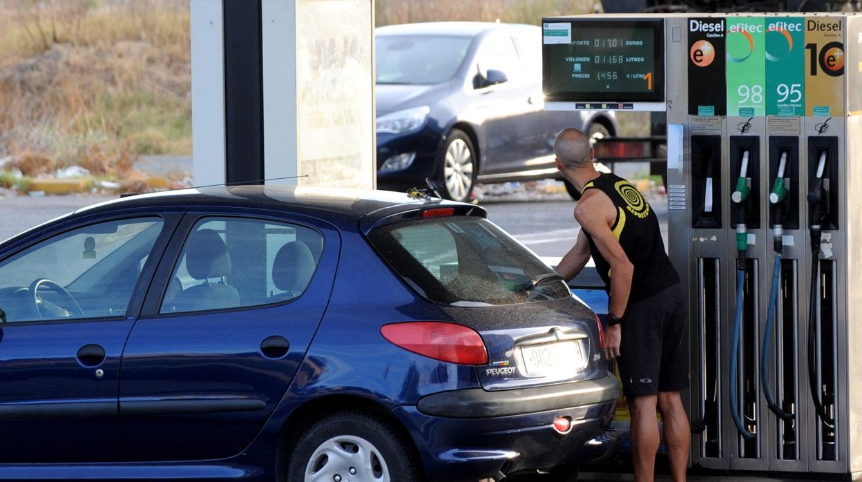 Un cliente se sirve gasolina en un surtidor de una gasolinera de Sevilla.