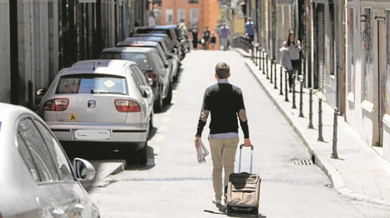 Un joven se marcha de su vivienda con una maleta de ruedas