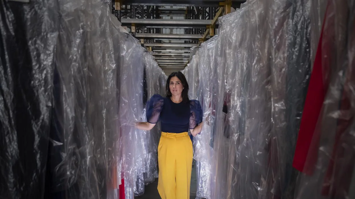 Carmen Osuna posa entre vestidos de su colección en el almacén donde los guarda