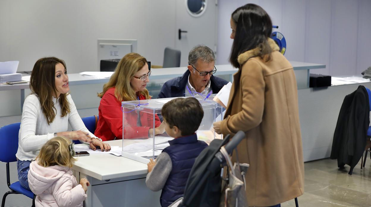 Una mujer ejerce su derecho al voto junto a sus hijos en Sevilla