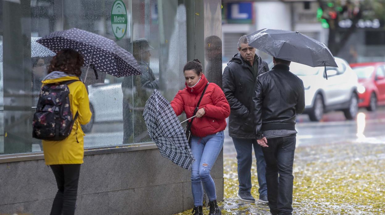 Varios ciudadanos se protegen de la lluvia y el viento en Sevilla