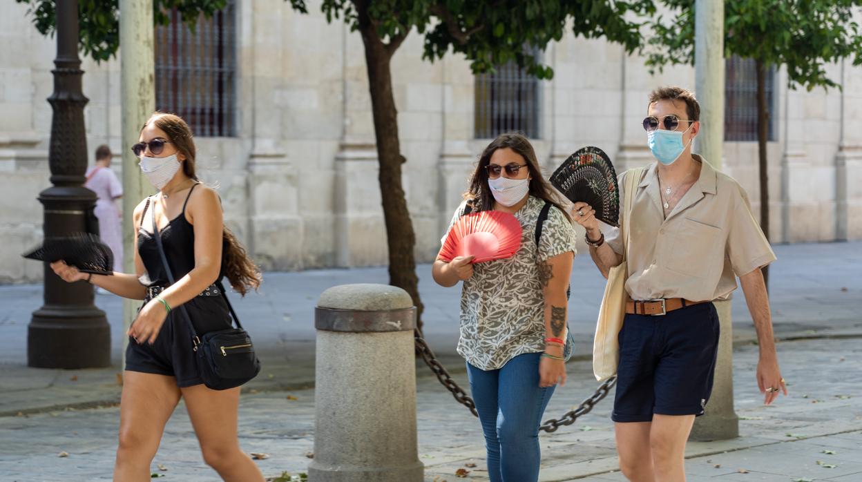 Tres personas pasean por la Plaza Nueva de Sevilla