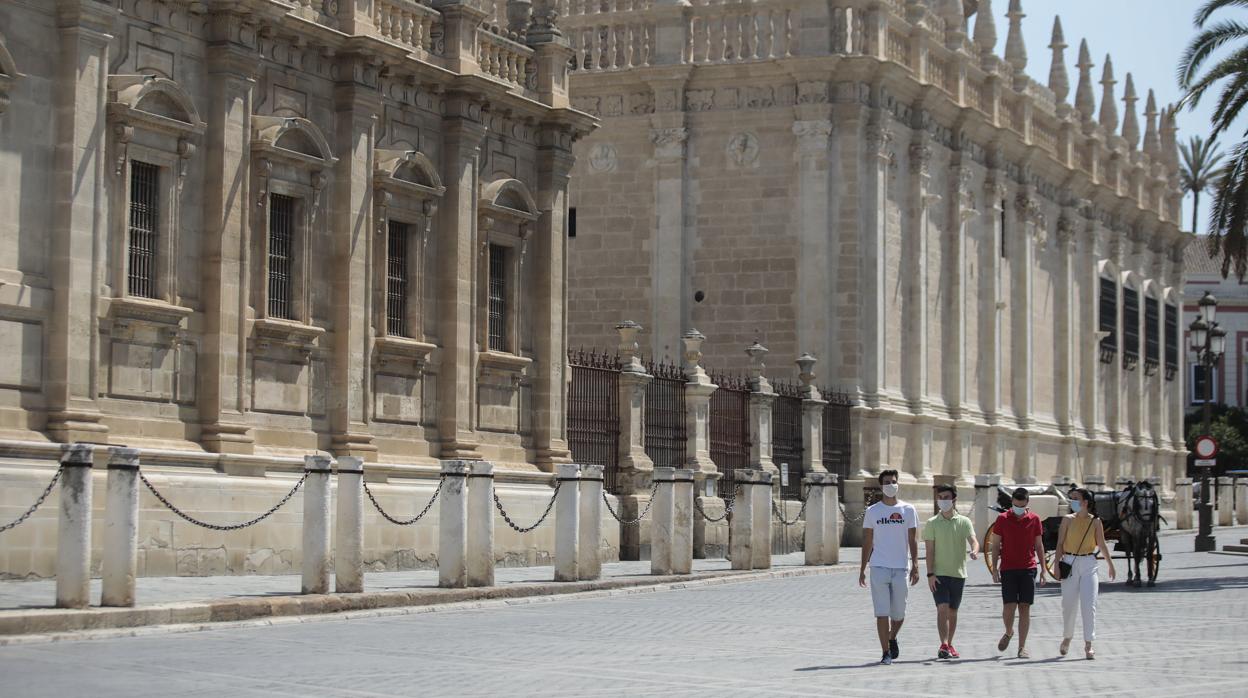 Varios turistas pasean por el desolado entorno de la Catedral de Sevilla