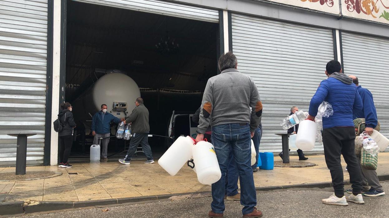 Vecinos de Paradas esperan en cola, con varias garrafas de plástico, su turno para recibir agua del camión cisterna